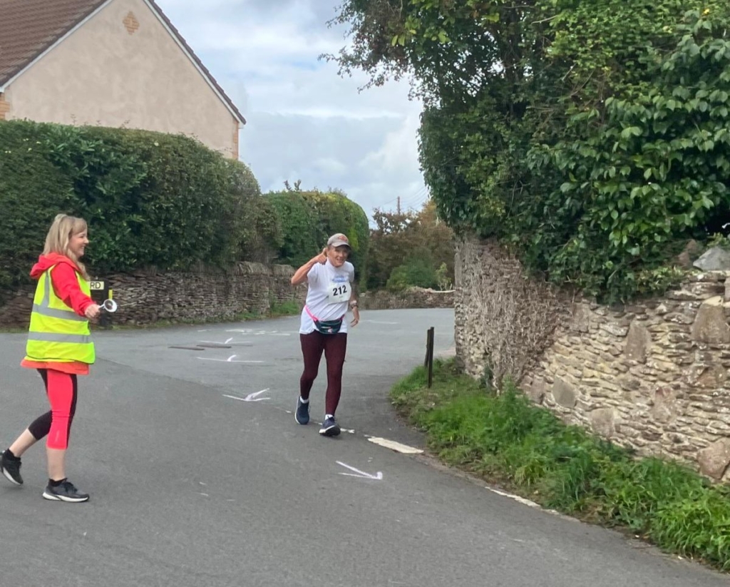 Fundraiser, Jo in action running through Frampton Cotterell guided by a race marshal.  